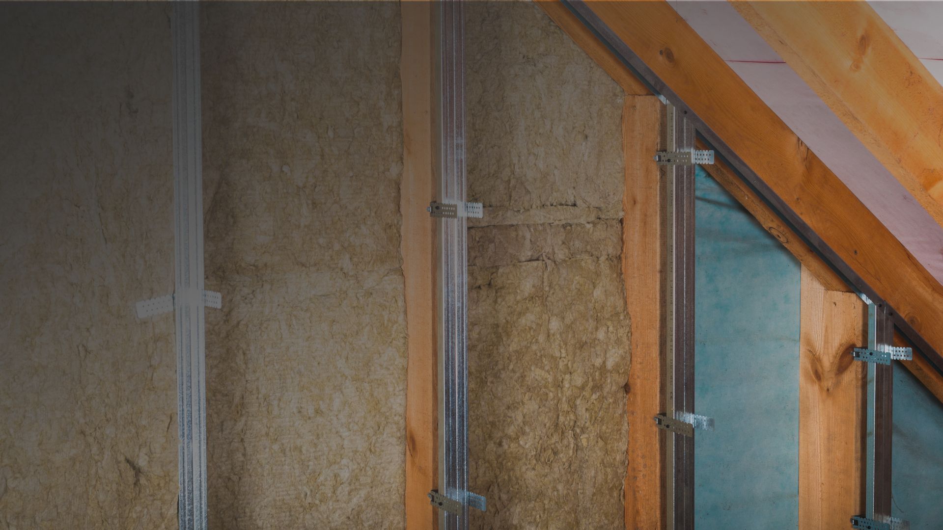 Installer fitting mineral wool loft insulation in a UK home attic